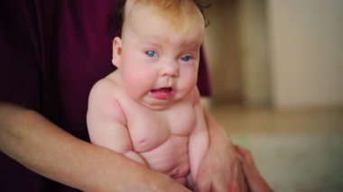 Bir yetişkin tarafından desteklenirken bebek dik oturur, çaba gösterir ve odaklanır.