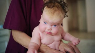 Bir yetişkin tarafından desteklenirken bebek dik oturur, çaba gösterir ve odaklanır.