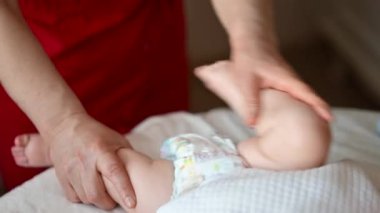 Bakıcı bebekle hareket egzersizi yapıyor.