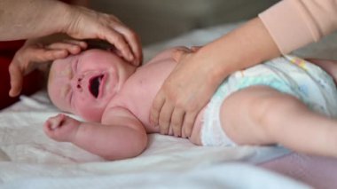Bir bebek ağlarken, bir bakıcı yumuşak bir yüzeye nazikçe masaj yapar.