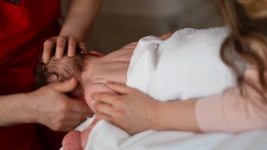 Bir bebek karnının üzerine yatarken bebek bakıcısı bebeğin kafasına nazikçe masaj yapar.