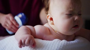 Baby lying on their tummy while an adult massages them and performs mobility exercises