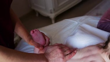 Yatakta bebekle ilgilenirken bir bebeğin küçük ayağını tutan bakıcıya yaklaş.