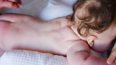 Bebek karnının üstünde yatarken bir yetişkin onlara masaj yapıyor ve hareket egzersizleri yapıyor.