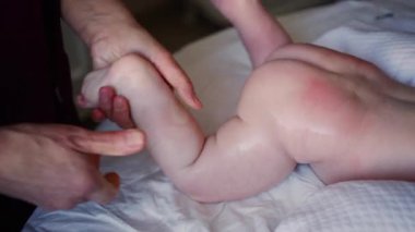 Bebek karnının üstünde yatarken bir yetişkin onlara masaj yapıyor ve hareket egzersizleri yapıyor.