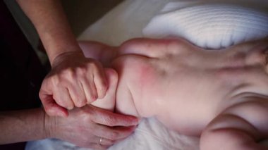 Bakıcı bebekle hareket egzersizi yapıyor.