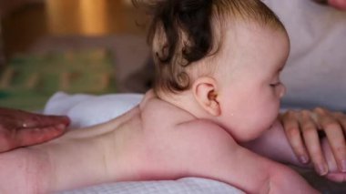Bebek karnının üstünde yatarken yetişkin ellerinin nazikçe sırtına masaj yapması.