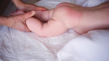 Bebek karnının üstünde yatarken bir yetişkin onlara masaj yapıyor ve hareket egzersizleri yapıyor.