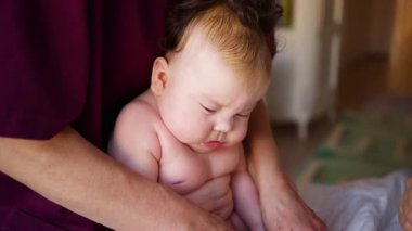 Bakıcı bebekle hareket egzersizi yapıyor.