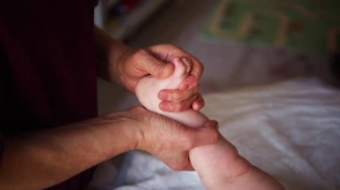 Yetişkinlerin ellerini kapat. Bebeğin ayağına ve tabanına nazikçe masaj yap.