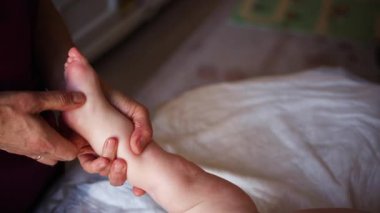 Yetişkinlerin ellerini kapat. Bebeğin ayağına ve tabanına nazikçe masaj yap.