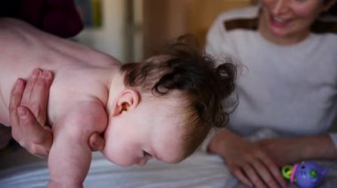 Bakıcı anneye yakın bir yerde bebekle hareket egzersizi yapıyor.