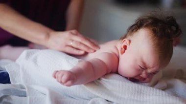 Bebek karnının üstünde yatarken bir yetişkin onlara masaj yapıyor ve hareket egzersizleri yapıyor.