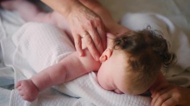 Bebek karnının üstünde yatarken bir yetişkin onlara masaj yapıyor ve hareket egzersizleri yapıyor.