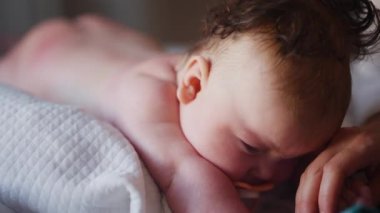 Bebek karnının üstünde yatarken bir yetişkin onlara masaj yapıyor ve hareket egzersizleri yapıyor.