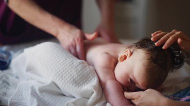 Bebek karnının üstünde yatarken bir yetişkin onlara masaj yapıyor ve hareket egzersizleri yapıyor.