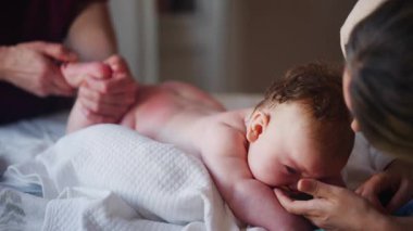 Bebek karnının üstünde yatarken bir yetişkin onlara masaj yapıyor ve hareket egzersizleri yapıyor.