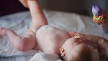 Bakıcı bebekle hareket egzersizi yapıyor. Oyuncak dikkatini dağıtıyor.