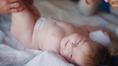 Bakıcı bebekle hareket egzersizi yapıyor. Oyuncak dikkatini dağıtıyor.