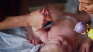 Bakıcı bebekle hareket egzersizi yapıyor. Oyuncak dikkatini dağıtıyor.