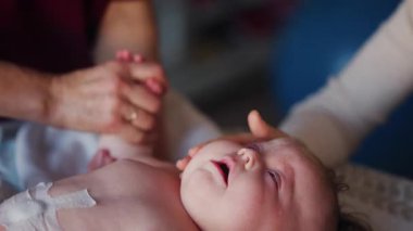 Bakıcı bebekle hareket egzersizi yapıyor.