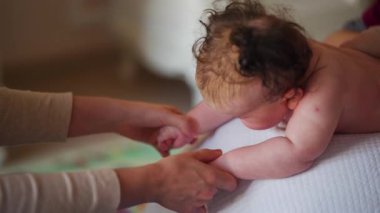 Yetişkinler bebeğin vücudunu desteklerken bebek dengeli bir topa konuyor.