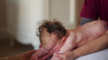 Yetişkinler bebeğin vücudunu desteklerken bebek dengeli bir topa konuyor.