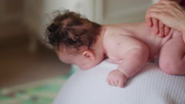 Bebek topun üstünde yatarken bakıcı nazikçe belini tutar.