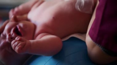 Yetişkinler bebeğin vücudunu desteklerken bebek dengeli bir topa konuyor.