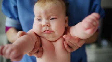 Baby lying on their back while an adult massages them and performs mobility exercises