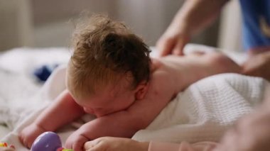 Bebek karnının üstünde yatarken bir yetişkin onlara masaj yapıyor ve hareket egzersizleri yapıyor.