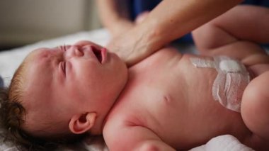 Bebek sırt üstü yatarken bir yetişkin onlara masaj yapıyor ve hareket egzersizleri yapıyor.