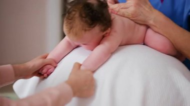 Yetişkinler bebeğin gövdesini ve omuzlarını desteklerken bebek de dengeli bir topun üzerine yerleştirilir.