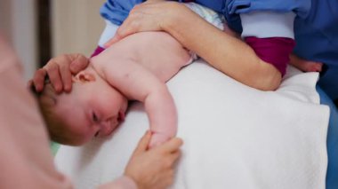 Yetişkinler bebeğin gövdesini ve omuzlarını desteklerken bebek de dengeli bir topun üzerine yerleştirilir.