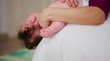 Yetişkinler bebeğin gövdesini ve omuzlarını desteklerken bebek dengeli bir topun üzerine yerleştirildi.