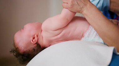 Yetişkinler bebeğin gövdesini ve omuzlarını desteklerken bebek dengeli bir topun üzerine yerleştirildi.