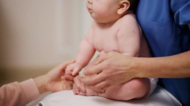 Yetişkinler bebeğin vücudunu desteklerken bebek dengeli bir topa konuyor.