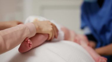 Yetişkinler bebeğin vücudunu desteklerken bebek dengeli bir topa konuyor.