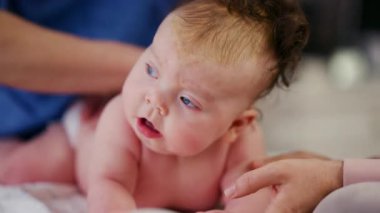 Baby lying on their tummy while an adult massages them and performs mobility exercises