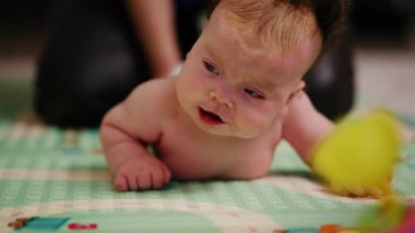 Karnında ve sırtında yastıklı bir yüzeye uzanmış küçük bir bebek.