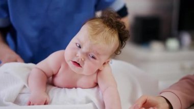 Bebek karnının üstünde yatarken bir yetişkin onlara masaj yapıyor ve hareket egzersizleri yapıyor.