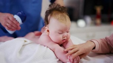 Baby lying on their tummy while an adult massages them and performs mobility exercises