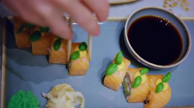 Çubuklar bir parça suşi alıp soya sosuna batırır.