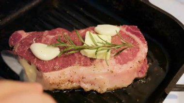 Izgara tavasında pişirirken bifteğe sarımsak ve tereyağı eklendi.