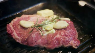 Sıcak ızgarada sarımsaklı ve biberiyeli bifteğin üzerine erimiş tereyağını kapat.