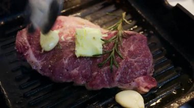 Sıcak ızgarada sarımsaklı ve biberiyeli bifteğin üzerine erimiş tereyağını kapat.