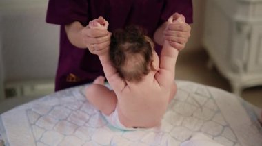 Yetişkinler, yumuşak bir yüzeye çıkmak için bebeğin ellerini tutarlar.