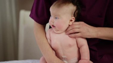 Bir yetişkin tarafından desteklenirken bebek dik oturur, çaba gösterir ve odaklanır.