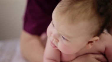 Baby sitting upright while being supported by an adult, showing effort and focus