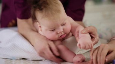 Bebek karnının üstünde yatarken bir yetişkin onlara masaj yapıyor ve hareket egzersizleri yapıyor.